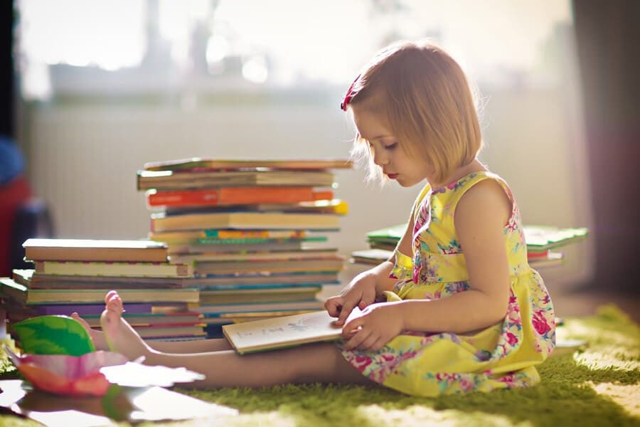 Young girl reading a stack of books Young girl reading a stack of books